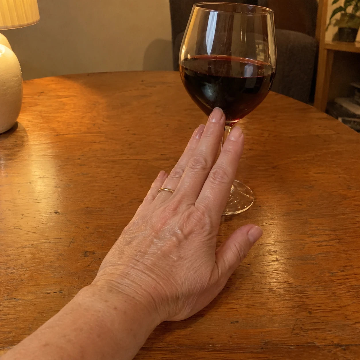 Hand pushing a full wine glass away