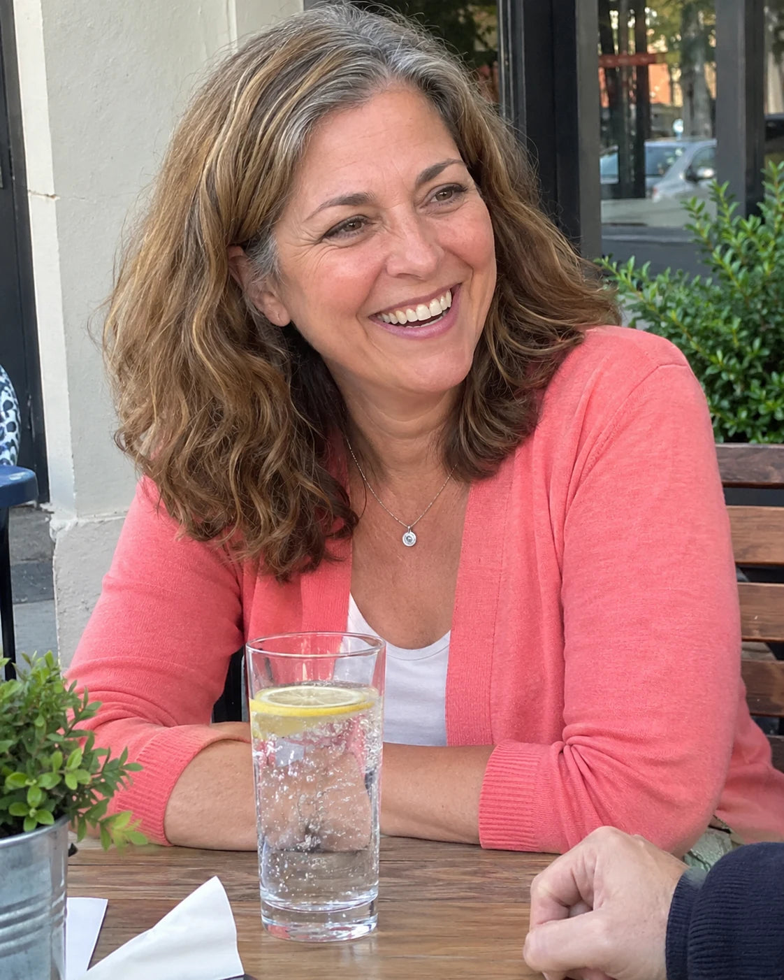 Denise laughing with a friend at an outdoor cafe table