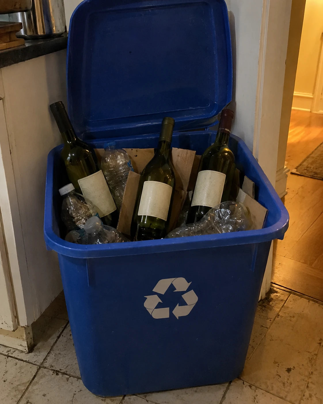 Recycling bin full of empty wine bottles in a dim kitchen