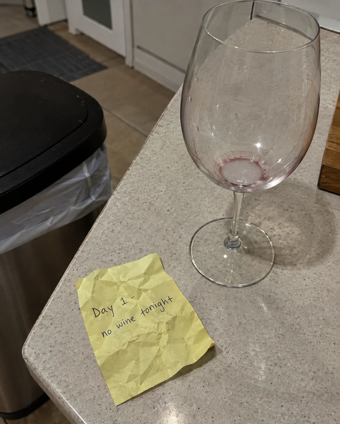 A crumpled resolution note next to an empty wine glass