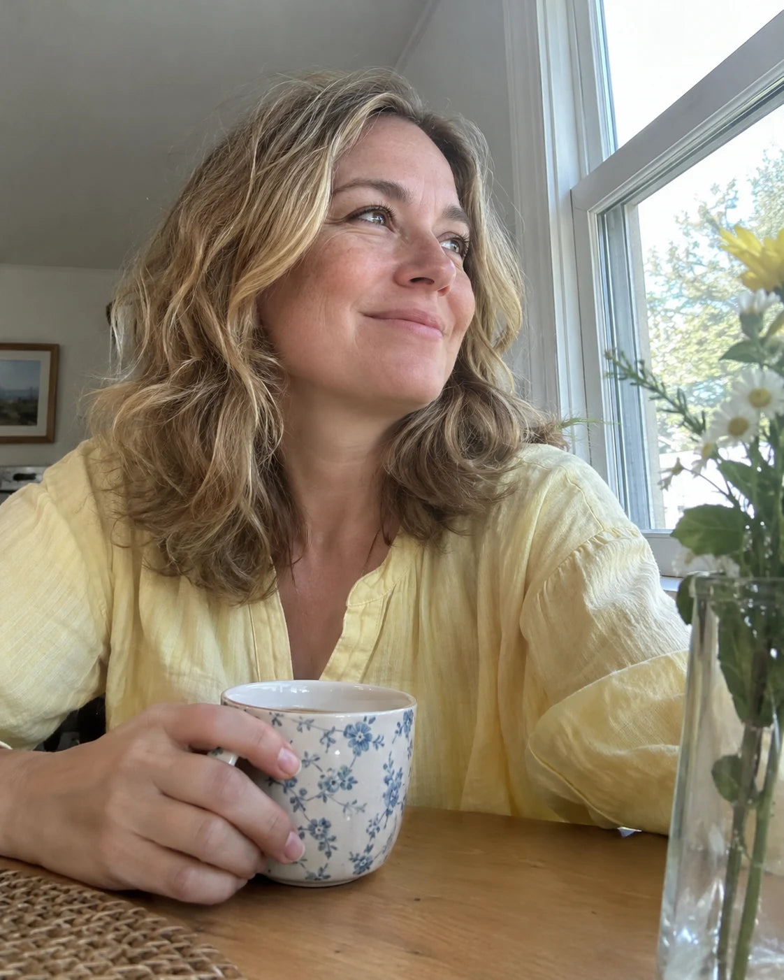 Woman smiling by a window in the morning light