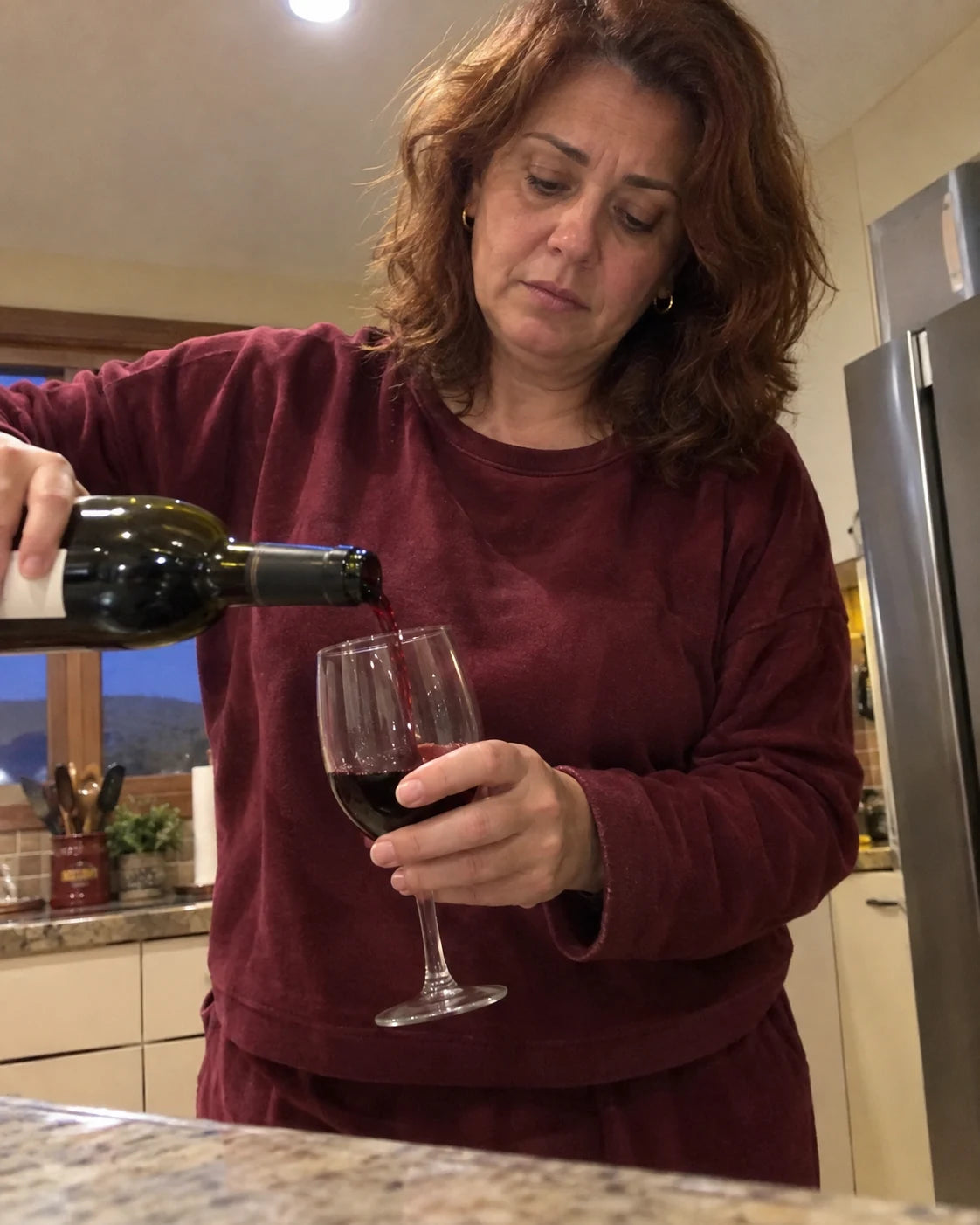 Woman pouring a glass of wine in the evening, conflicted expression